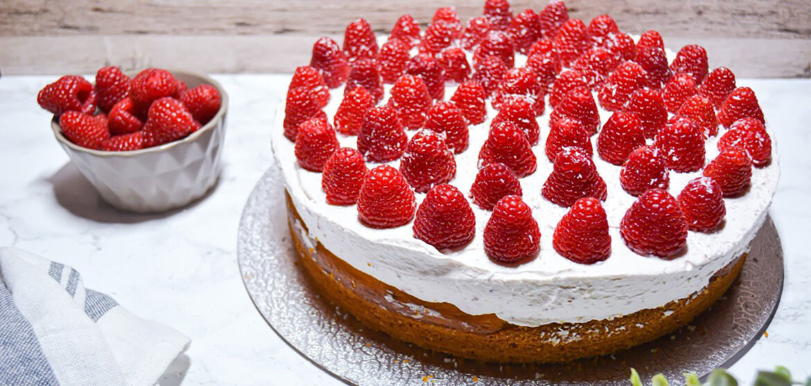 Himbeerkokosnuss Torte und eine Schale mit Himbeeren stehen auf Tisch