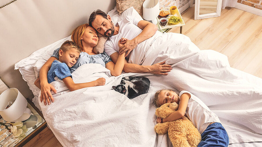 Vierköpfige Familie liegt gemeinsam im Bett und schläft